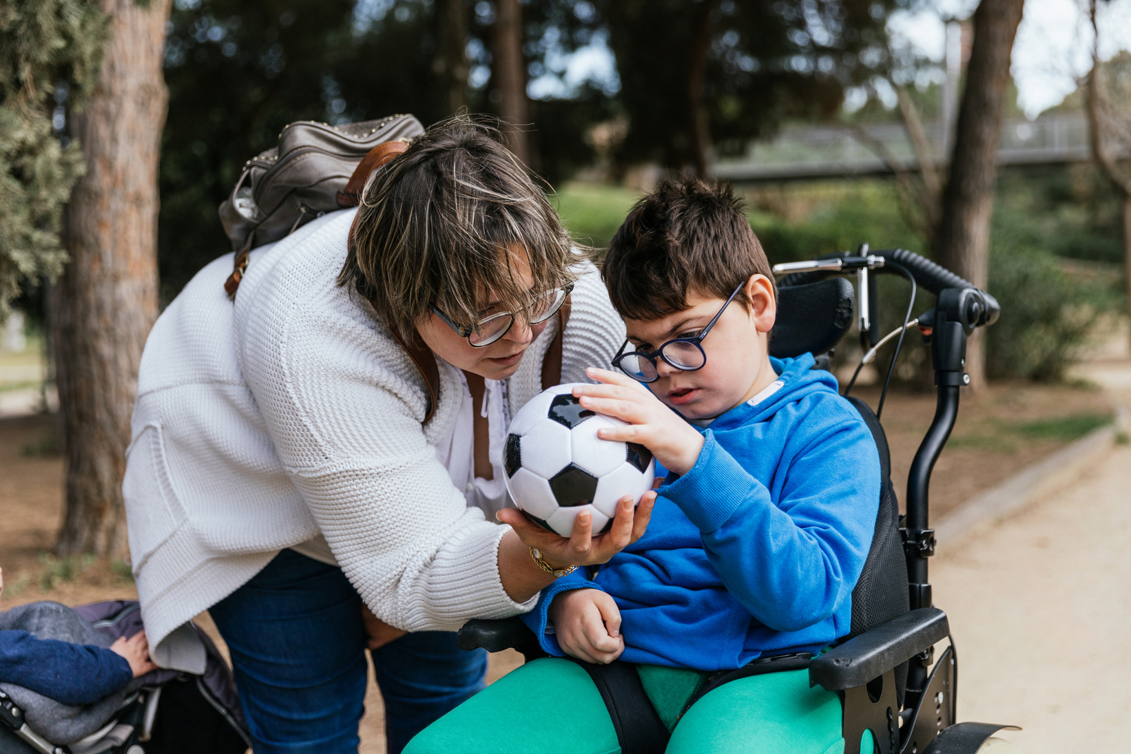 Child with Multiple Disabilities in a Wheelchair Playing with a Soccer Ball with Her Mother Outdoors